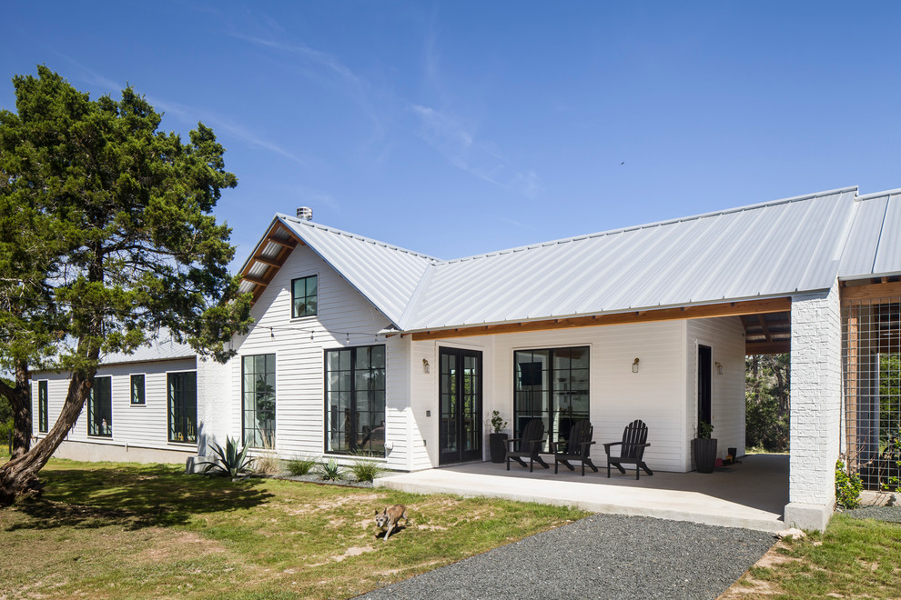 Réalisation d'une façade de maison blanche champêtre de plain-pied avec un toit en métal.