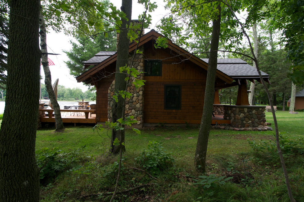 Esempio della facciata di una casa piccola marrone rustica a un piano con rivestimento in legno e tetto a capanna