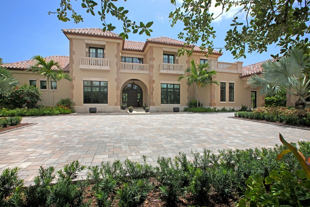 Example of a large tuscan beige two-story stucco exterior home design in Miami with a hip roof