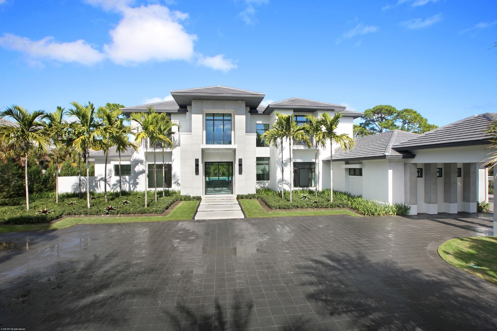 Example of a large island style white two-story stucco exterior home design in Miami