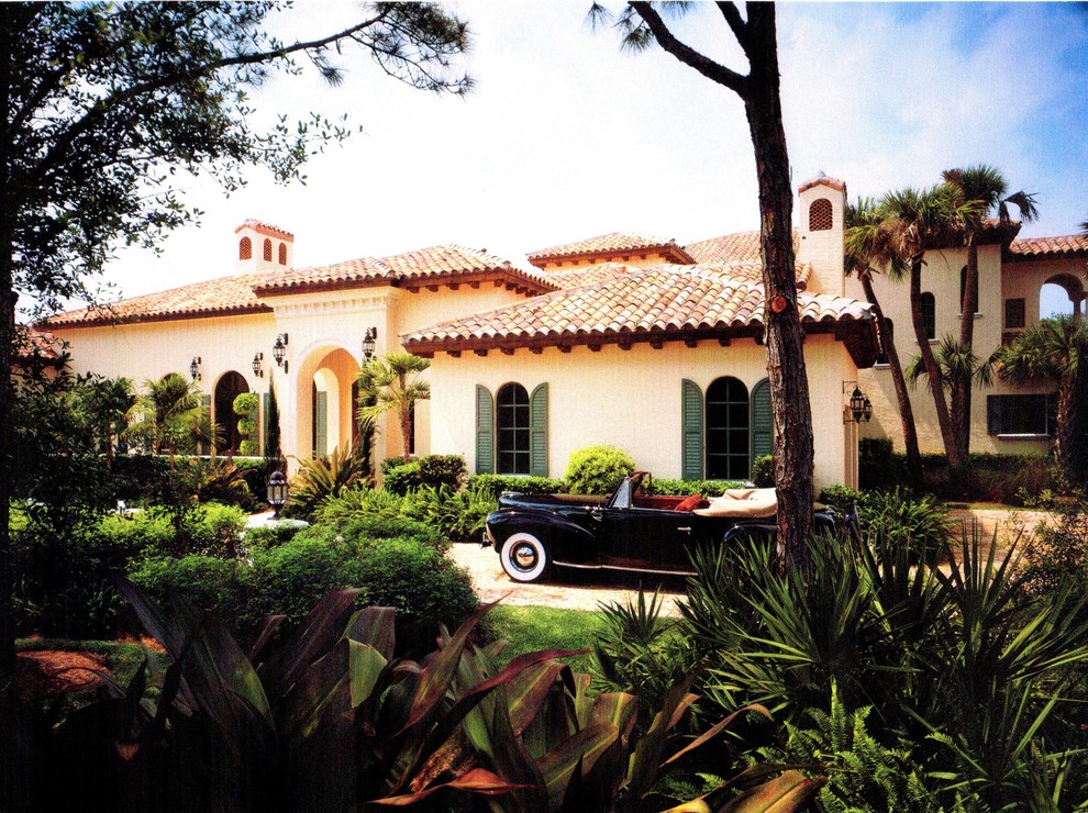 Example of a large tuscan beige two-story stucco house exterior design in Miami with a hip roof and a tile roof