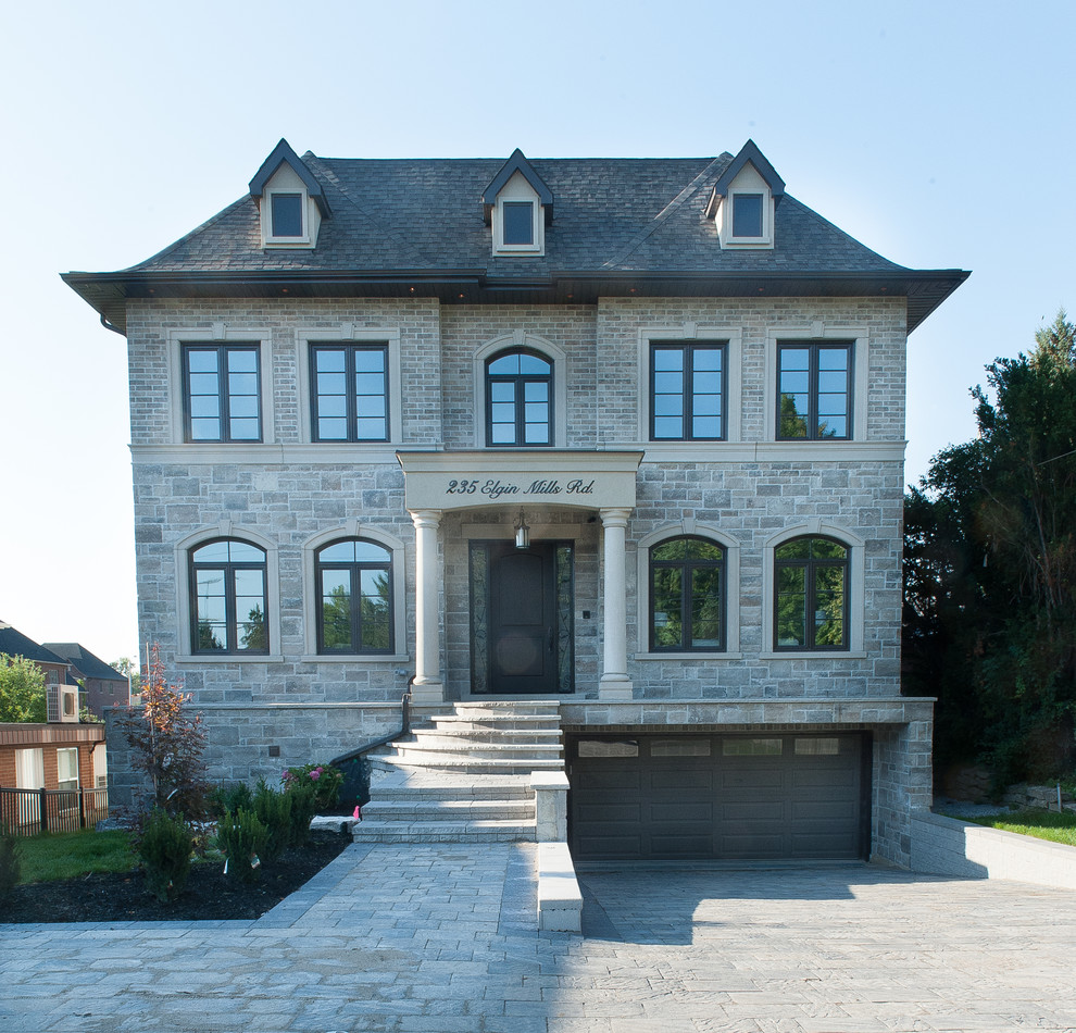 Стильный дизайн: большой, двухэтажный, серый частный загородный дом в стиле неоклассика (современная классика) с облицовкой из камня, двускатной крышей и черепичной крышей - последний тренд