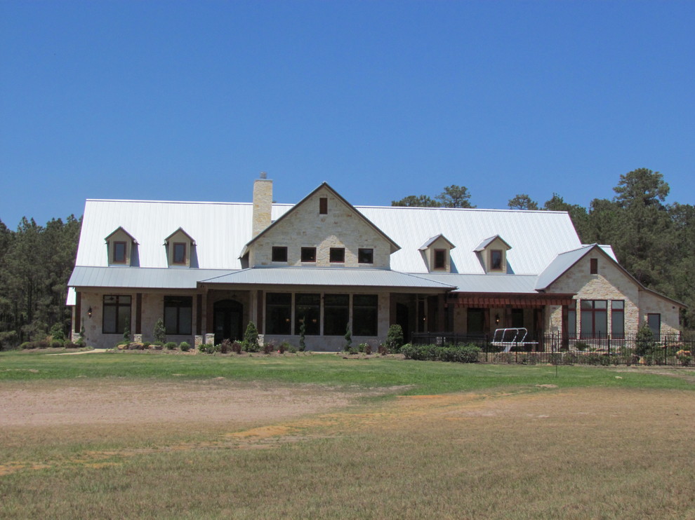 Foto della facciata di una casa grande beige country a due piani con rivestimento in pietra e tetto a capanna