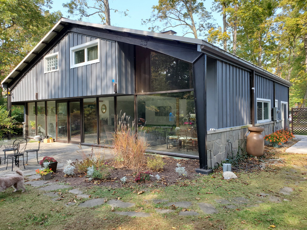 Ejemplo de fachada gris y blanca campestre pequeña de una planta con revestimiento de aglomerado de cemento, tejado a dos aguas, microcasa, tejado de metal y panel y listón