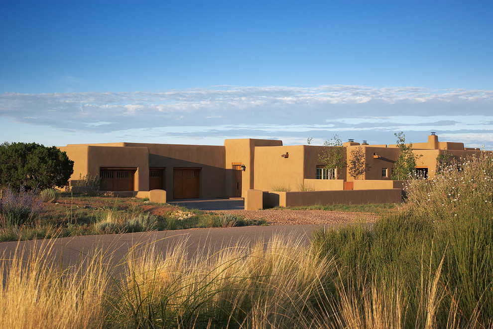 Mittelgroßes, Einstöckiges Mediterranes Einfamilienhaus mit Lehmfassade, beiger Fassadenfarbe, Flachdach und braunem Dach in Albuquerque