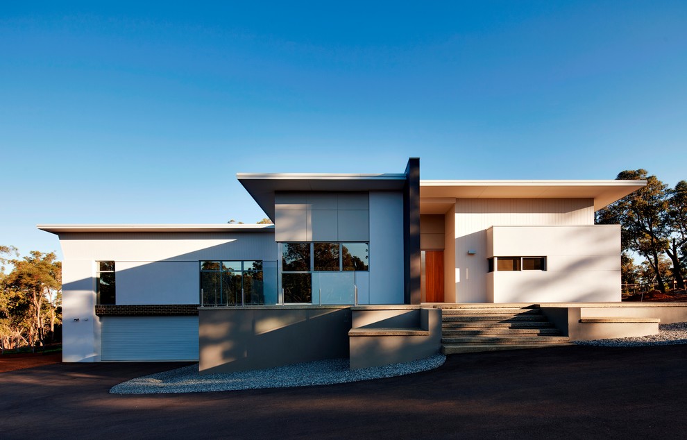 Inspiration för ett mellanstort vitt hus i flera nivåer, med fiberplattor i betong, platt tak och tak i metall