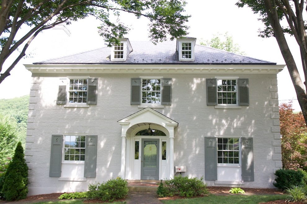 Imagen de fachada de casa blanca clásica de dos plantas con revestimiento de ladrillo