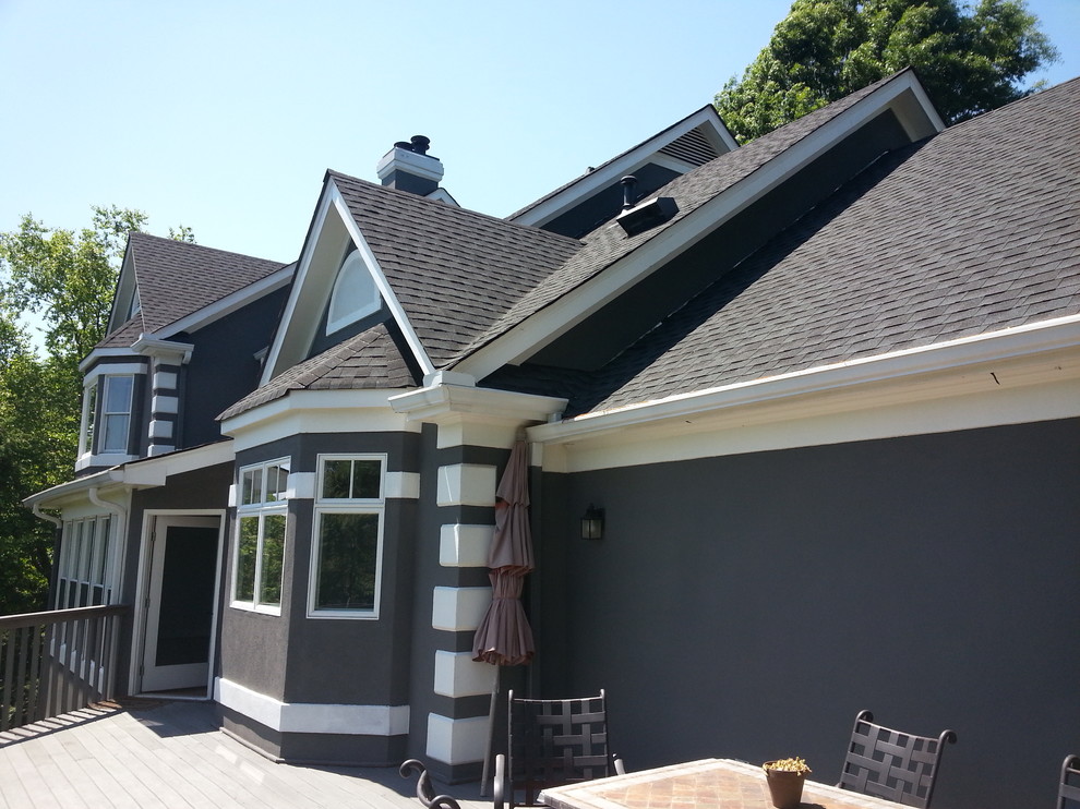 Example of a large classic gray one-story stucco exterior home design in Other with a shed roof