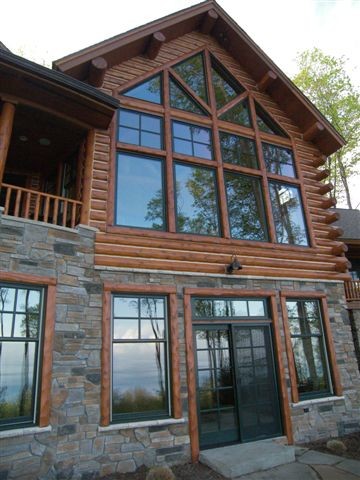 Ejemplo de fachada marrón rústica de tamaño medio de dos plantas con tejado a dos aguas y revestimientos combinados