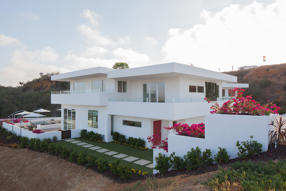 This is an example of a large and white contemporary two floor render detached house in San Diego with a flat roof.