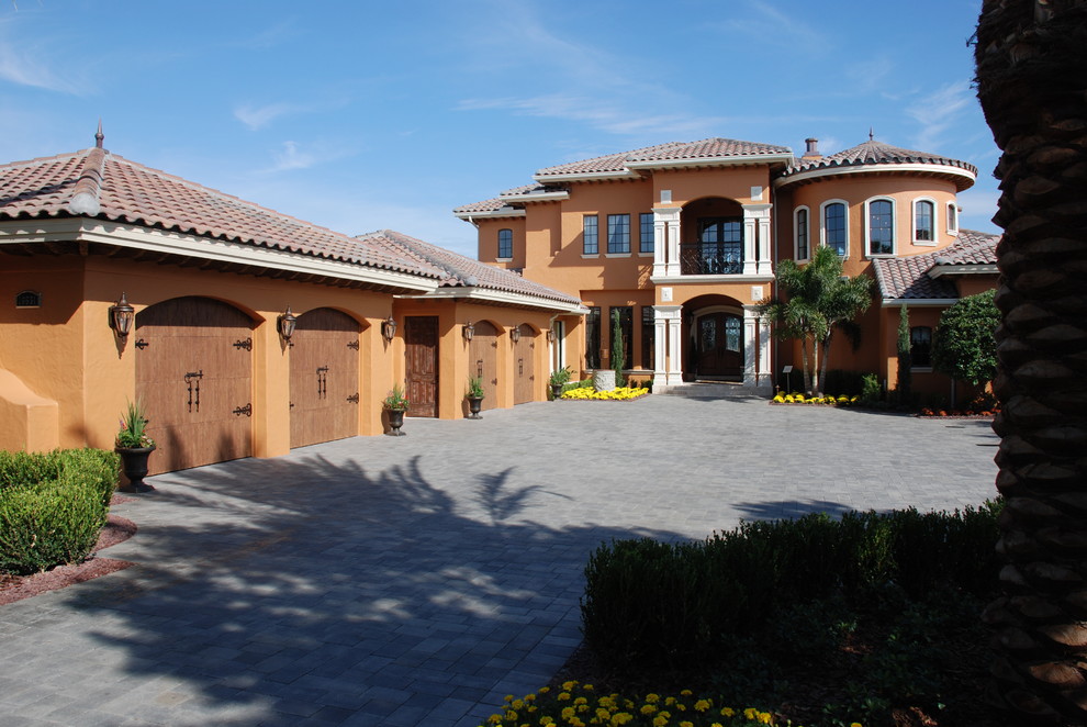Cette image montre une grande façade de maison beige méditerranéenne en stuc à un étage avec un toit à deux pans.