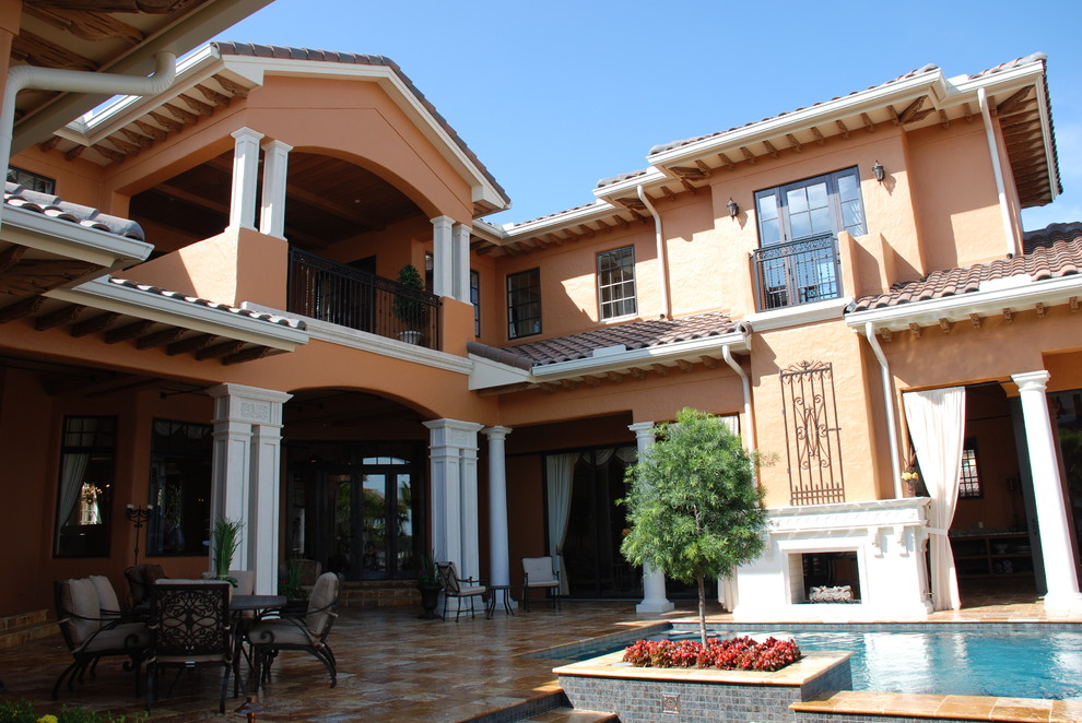 Пример оригинального дизайна: большой, двухэтажный, бежевый дом в средиземноморском стиле с облицовкой из цементной штукатурки и двускатной крышей
