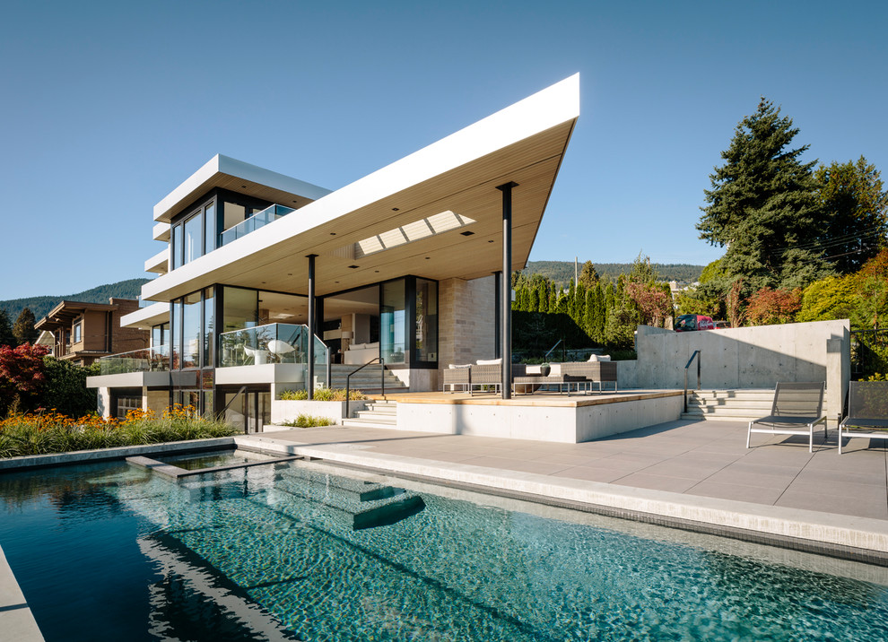 Large and beige contemporary detached house in Vancouver with three floors, stone cladding and a flat roof.