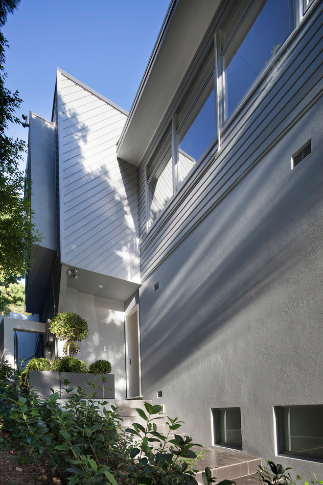 Idéer för mellanstora funkis grå flerfamiljshus, med två våningar, stuckatur, platt tak och tak i metall