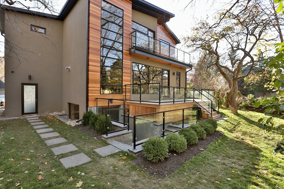 Expansive and beige contemporary split-level house exterior in Toronto with mixed cladding and a hip roof.