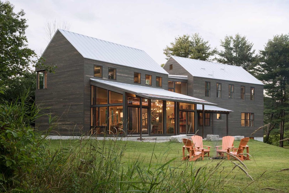 Exemple d'une grande façade de maison nature en bois à un étage avec un toit à deux pans et un toit en métal.