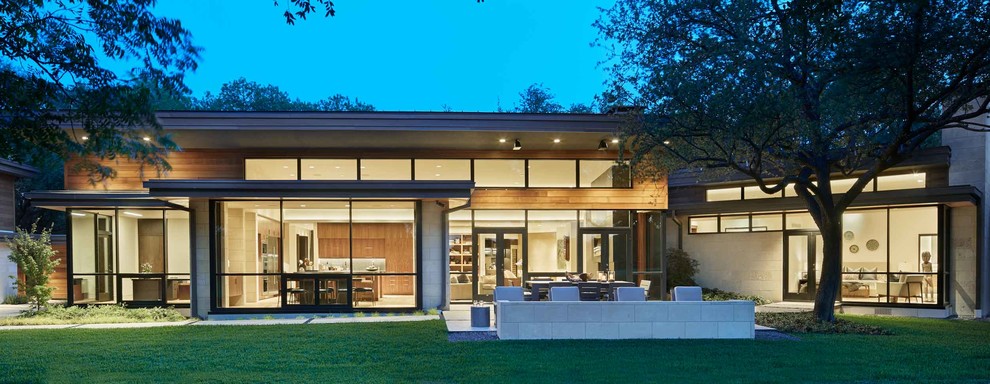 На фото: огромный, одноэтажный, коричневый частный загородный дом в стиле модернизм с комбинированной облицовкой, плоской крышей и крышей из смешанных материалов