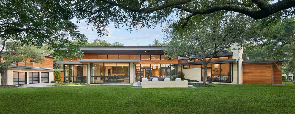 На фото: огромный, одноэтажный, коричневый частный загородный дом в стиле модернизм с комбинированной облицовкой, плоской крышей и крышей из смешанных материалов с