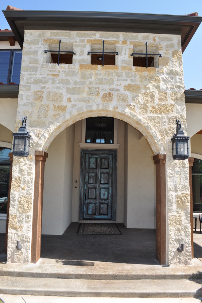 Large mediterranean beige two-story stone exterior home idea in Austin with a hip roof