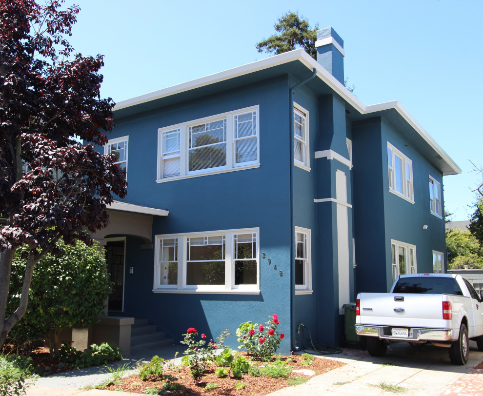 На фото: большой, двухэтажный, синий дуплекс в классическом стиле с облицовкой из цементной штукатурки, плоской крышей и входной группой