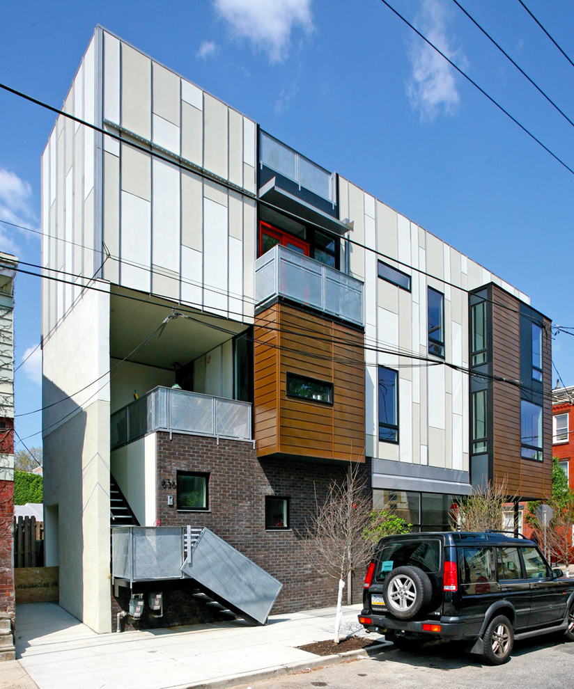Inspiration for a large industrial beige three-story mixed siding flat roof remodel in Philadelphia