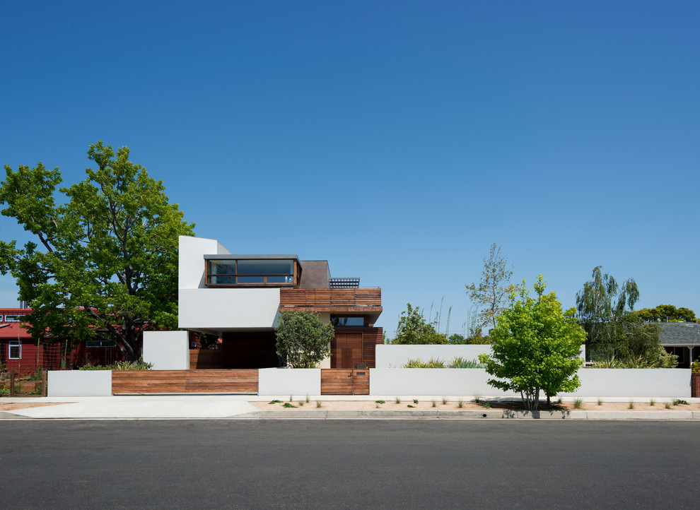 Esempio della facciata di una casa moderna a tre piani con rivestimenti misti e tetto piano