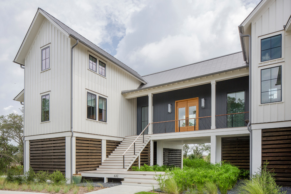Réalisation d'une façade de maison métallique et blanche champêtre à un étage avec un toit à deux pans et un toit en métal.