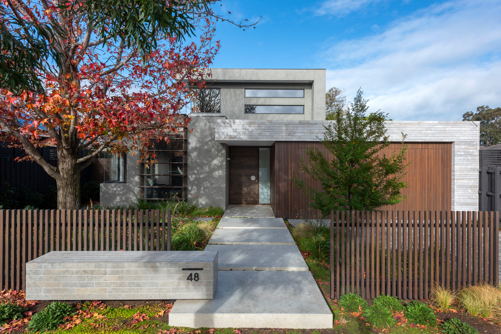 Diseño de fachada de casa gris contemporánea de dos plantas con tejado plano y revestimientos combinados