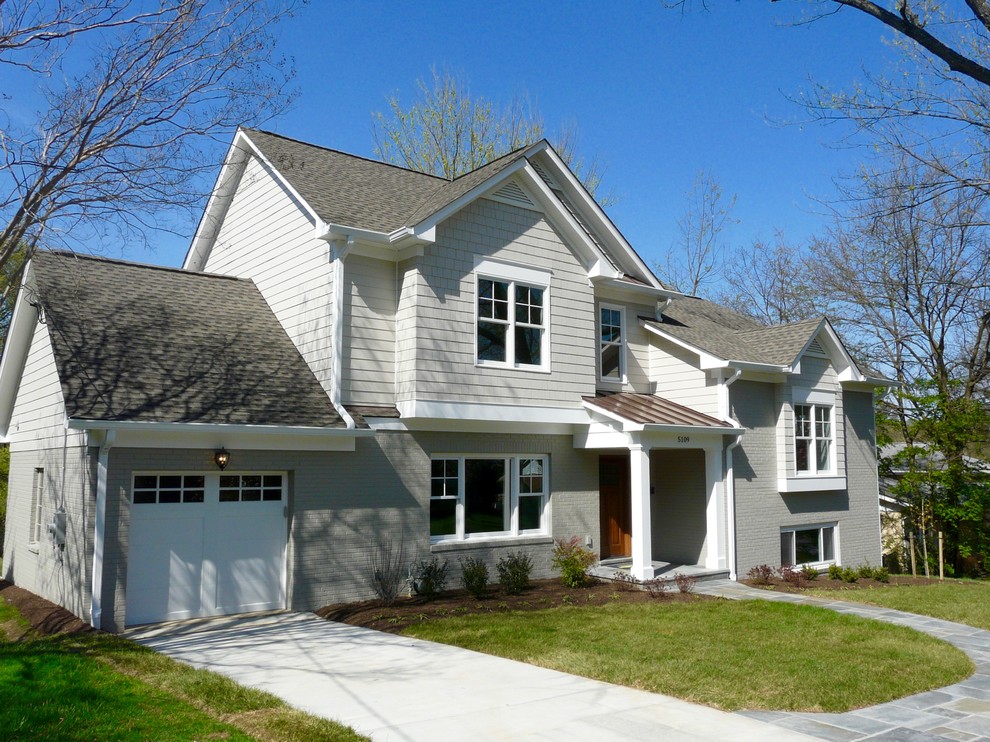 На фото: большой, серый дом в стиле неоклассика (современная классика) с разными уровнями, комбинированной облицовкой и двускатной крышей с