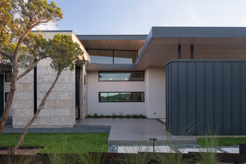 Ejemplo de fachada de casa beige contemporánea grande de una planta con revestimientos combinados, tejado plano y tejado de metal