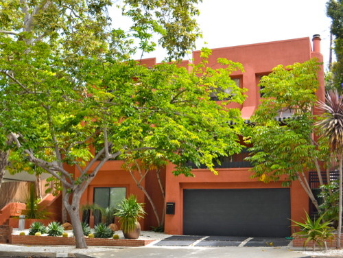 Inspiration pour une façade de maison rouge minimaliste en stuc de taille moyenne et à un étage avec un toit plat.