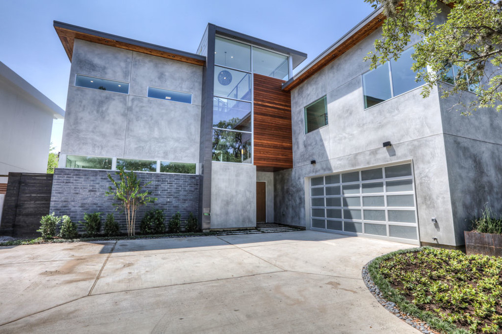 Mittelgroßes, Zweistöckiges Modernes Einfamilienhaus mit Betonfassade, grauer Fassadenfarbe, Flachdach und Blechdach in Houston