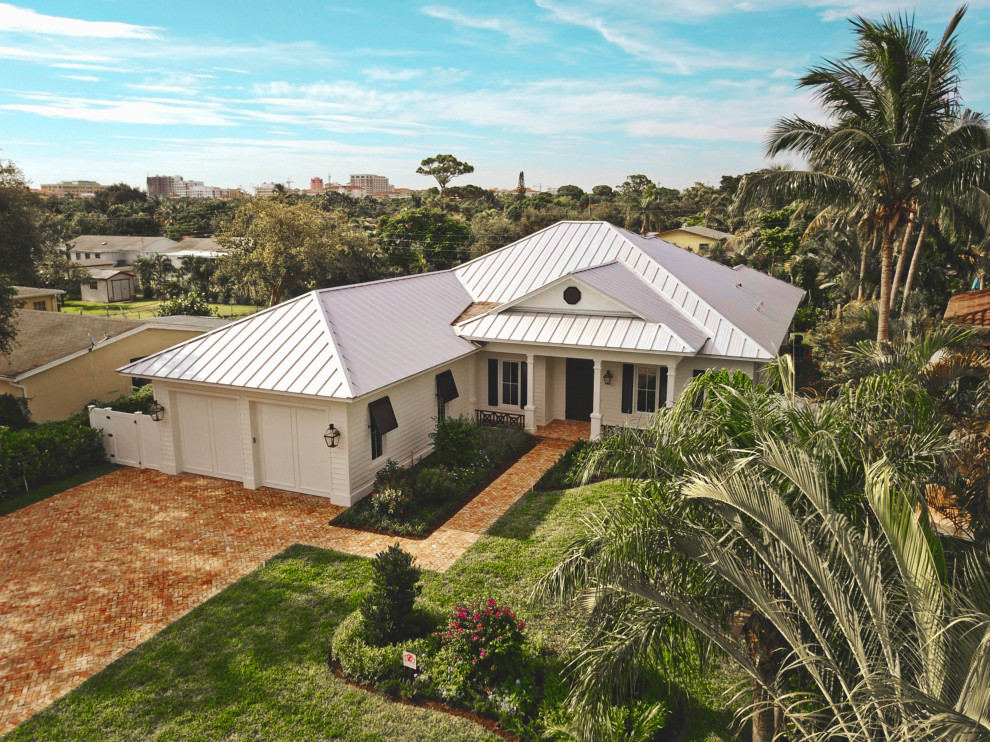 На фото: большой, одноэтажный, белый частный загородный дом в современном стиле с облицовкой из цементной штукатурки, вальмовой крышей и металлической крышей с
