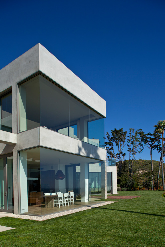 Cette image montre une grande façade de maison grise marine en béton à un étage avec un toit plat.
