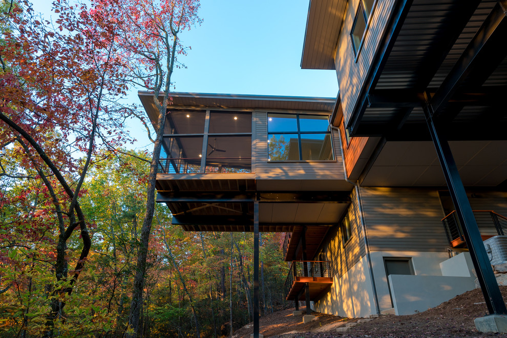 Cette photo montre une façade de maison grise montagne en bois de taille moyenne et à un étage avec un toit plat.