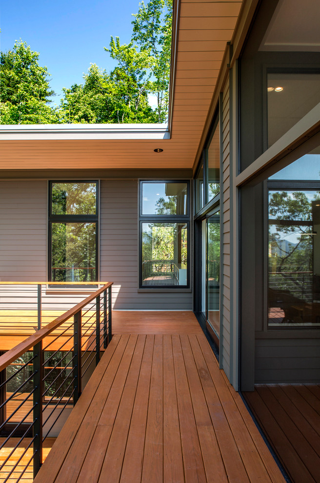 Réalisation d'une façade de maison grise chalet en bois de taille moyenne et à un étage avec un toit plat.