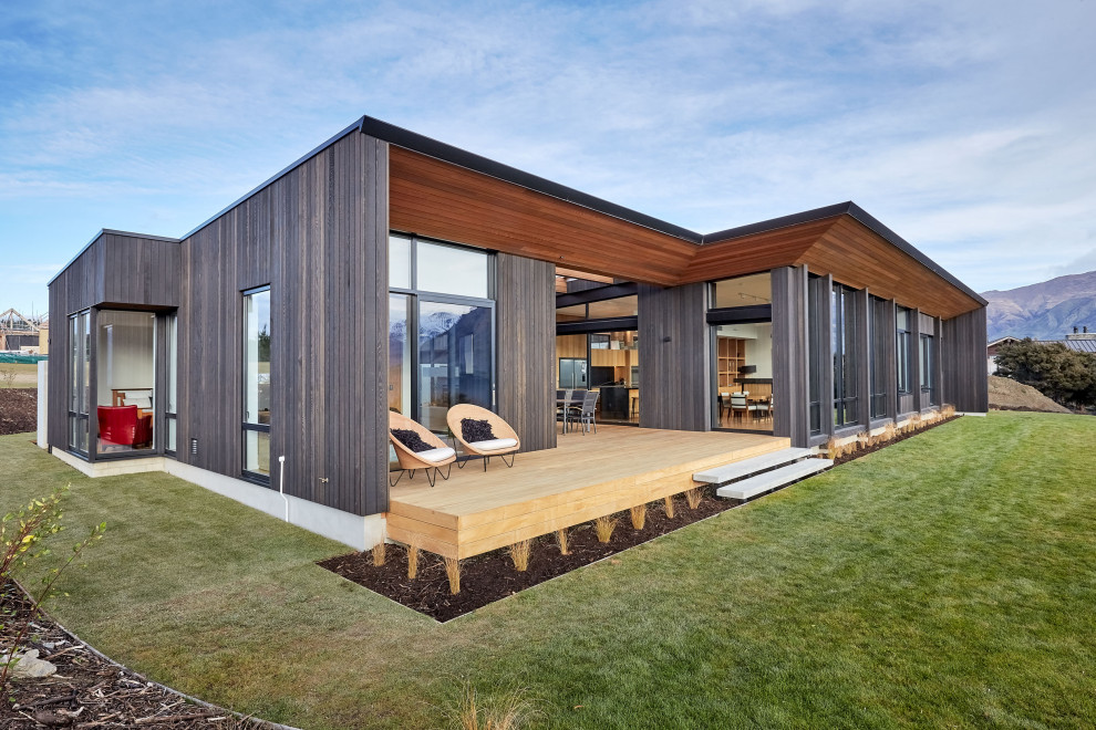 Cette image montre une très grande façade de maison noire design en bois de plain-pied.