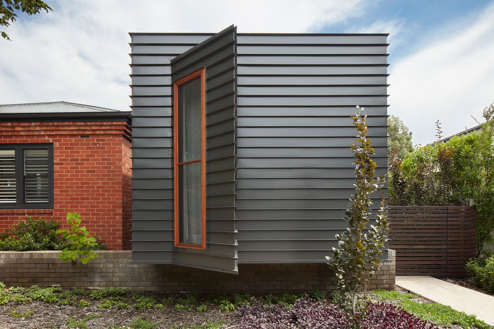 Diseño de fachada de casa negra contemporánea de tamaño medio de una planta con revestimiento de metal, tejado plano y tejado de metal