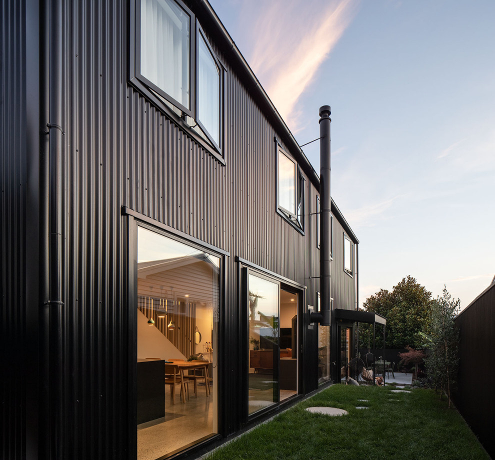 Ejemplo de fachada de casa negra actual de tamaño medio de dos plantas con revestimiento de metal, tejado a dos aguas y tejado de metal