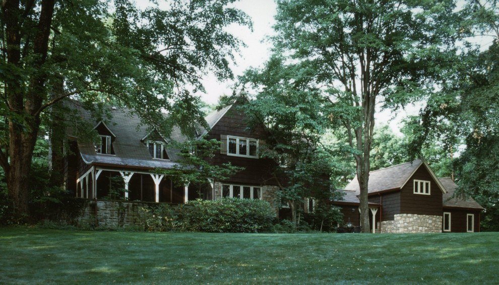 Стильный дизайн: большой, двухэтажный, коричневый дом в классическом стиле с облицовкой из камня и полувальмовой крышей - последний тренд