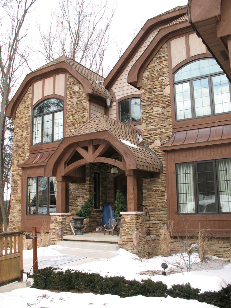 Imagen de fachada de casa marrón tradicional grande de dos plantas con revestimientos combinados, tejado a doble faldón y tejado de teja de madera