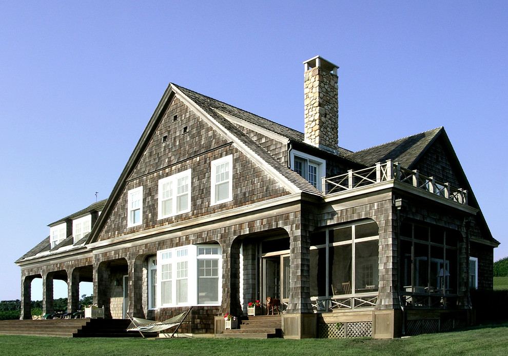 Modelo de fachada marrón tradicional grande de tres plantas con revestimiento de madera y tejado a dos aguas