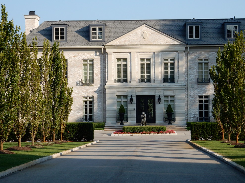 Immagine della facciata di una casa ampia bianca classica a tre piani con rivestimento in pietra e falda a timpano