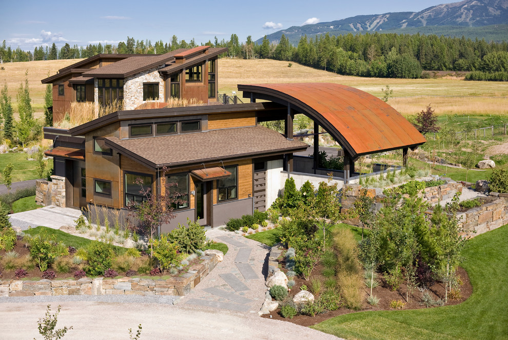 Foto della villa grande marrone contemporanea a due piani con rivestimenti misti, tetto piano e copertura in metallo o lamiera