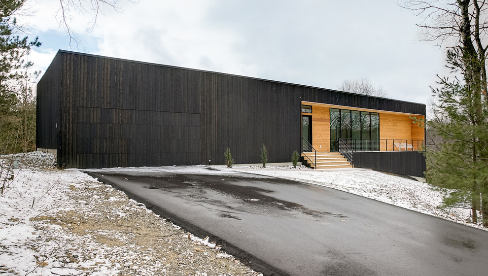 На фото: деревянный, черный, одноэтажный частный загородный дом среднего размера в стиле модернизм с плоской крышей