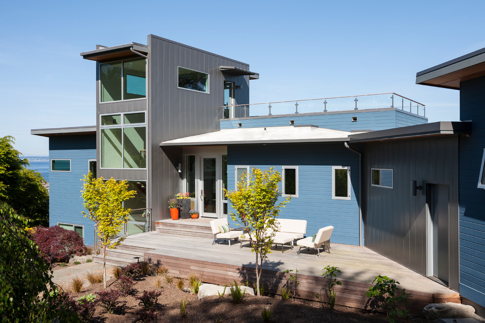 Bild på ett stort funkis blått hus, med blandad fasad, platt tak, tre eller fler plan och tak i metall