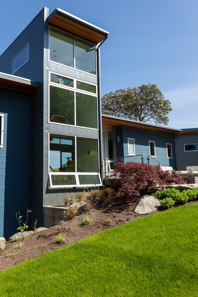 На фото: синий дом в современном стиле с комбинированной облицовкой и односкатной крышей с