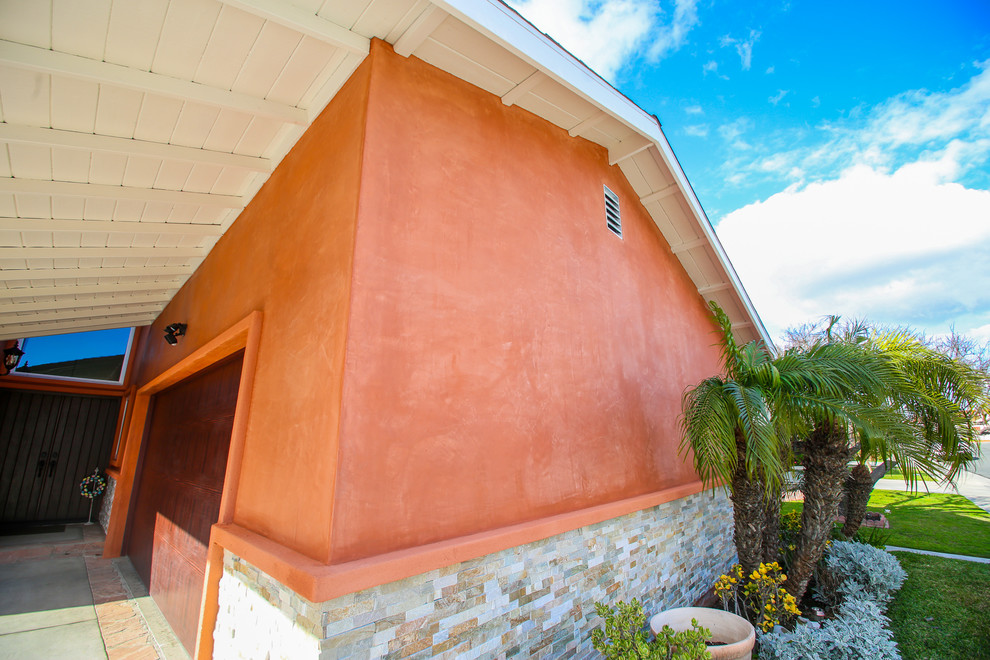 На фото: одноэтажный частный загородный дом среднего размера в стиле ретро с облицовкой из цементной штукатурки и двускатной крышей с