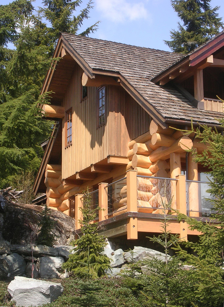 Imagen de fachada de casa marrón rústica grande de tres plantas con revestimiento de piedra y tejado a doble faldón