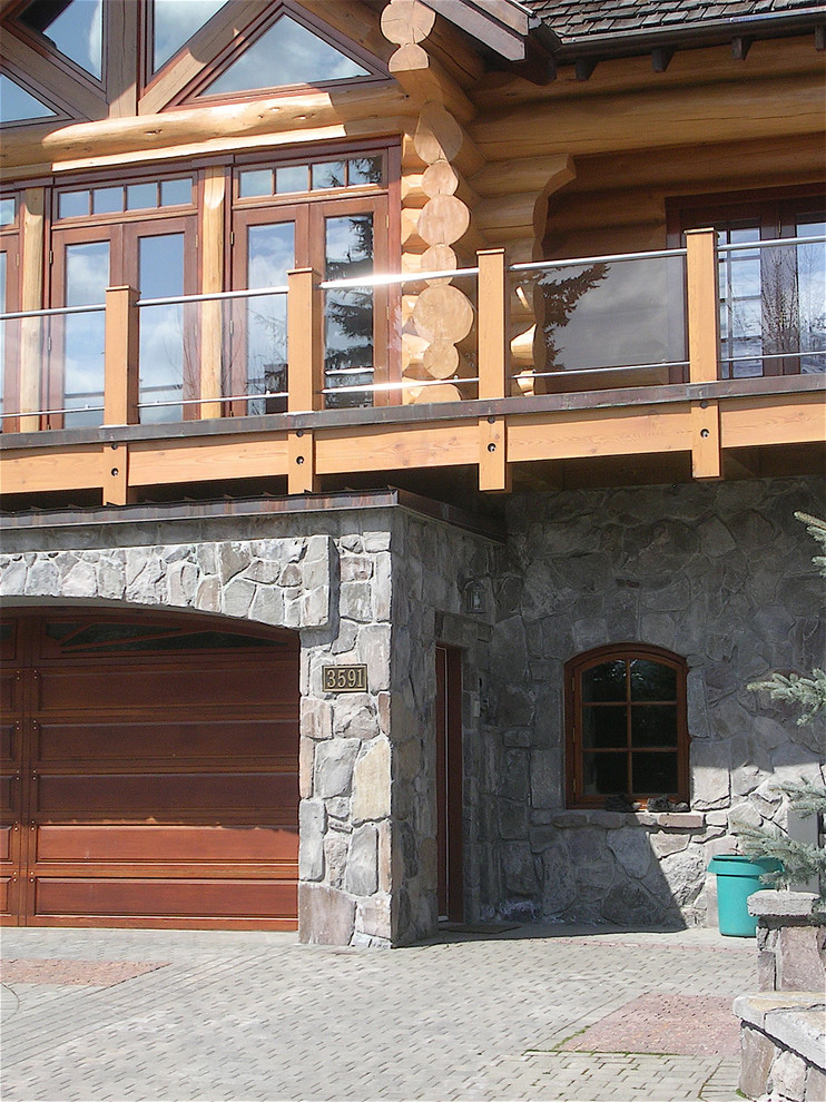 Photo of a large and brown rustic detached house in Vancouver with three floors, stone cladding and a mansard roof.